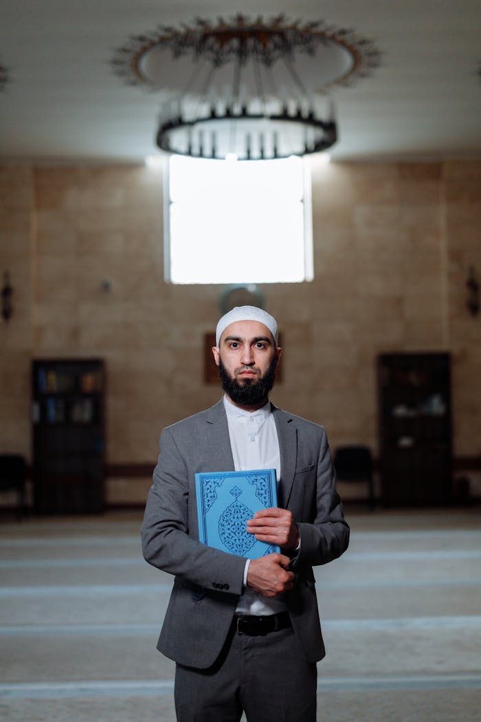 Man in Black Suit Jacket Holding Blue Book